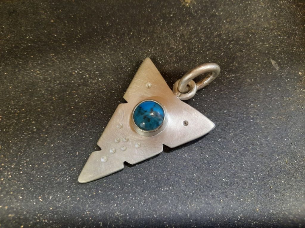 A solid silver 'arrow' pendant set with student's own turquoise